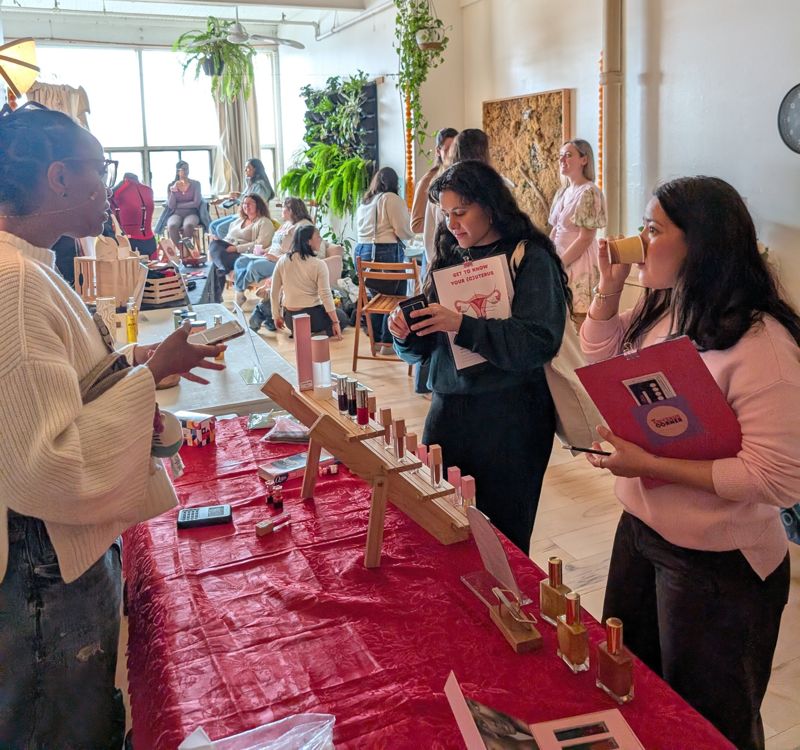 Attendees chatting with a vendor at a wellness pop-up table